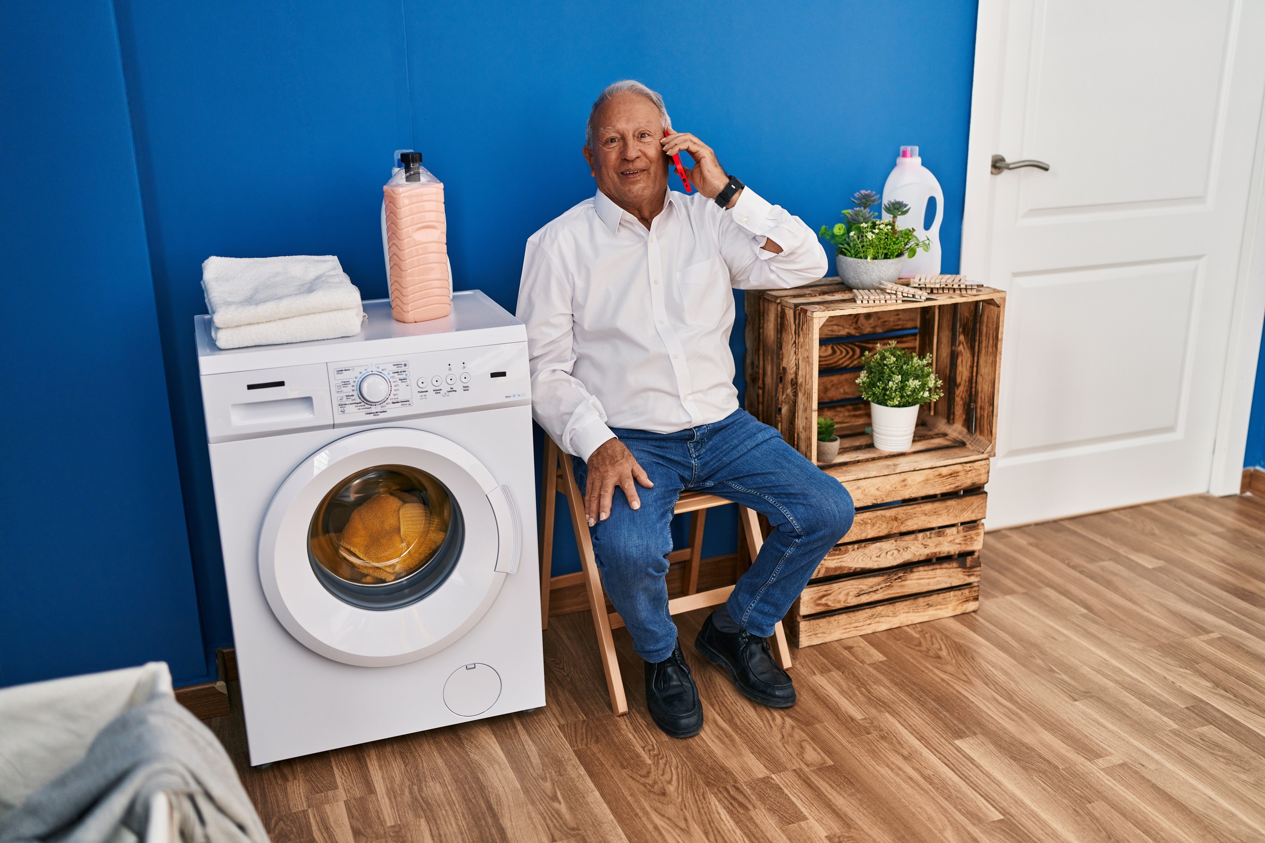 senior-man-talking-smartphone-waiting-washing-machine-laundry-room(1)